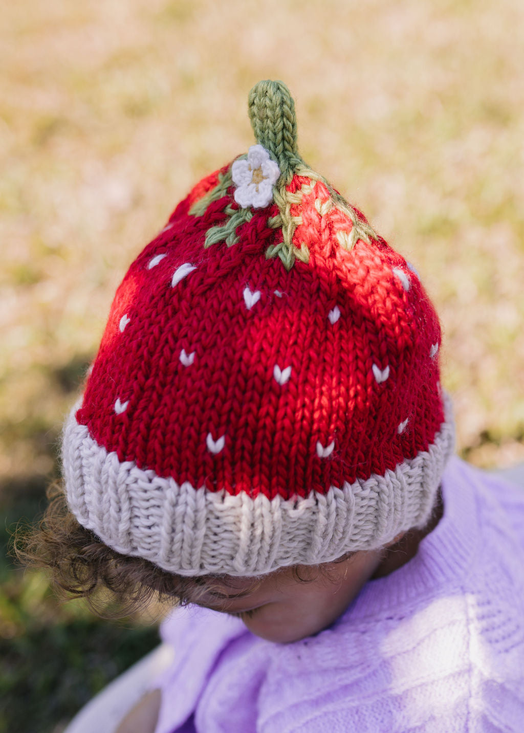Strawberry Beanie – kids hand-knitted beanie with strawberry, flower, and leaf design in soft wool blend shown on child - top view – Acorn Kids