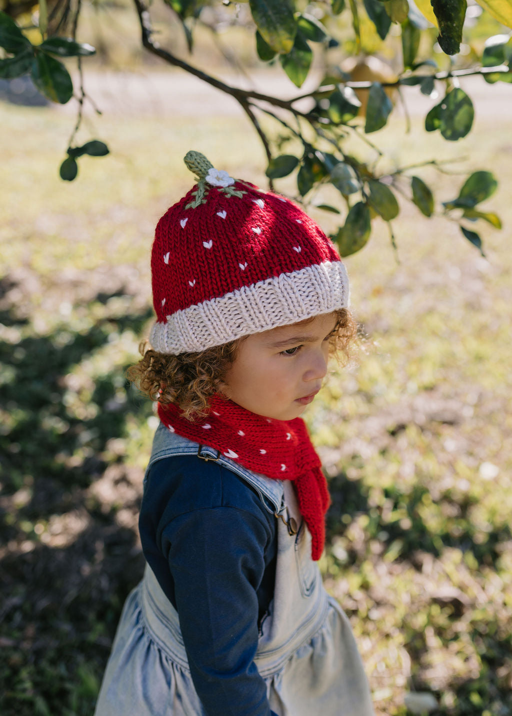 Strawberry Beanie and Cross Over Scarf – kids hand-knitted red and white scarf with strawberry design in soft wool blend – shown on child - side view - Acorn Kids