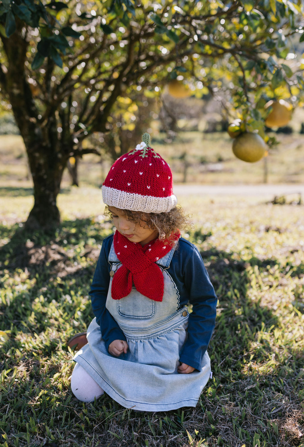 Strawberry Beanie – kids hand-knitted beanie with strawberry, flower, and leaf design in soft wool blend shown on child - side view – Acorn Kids