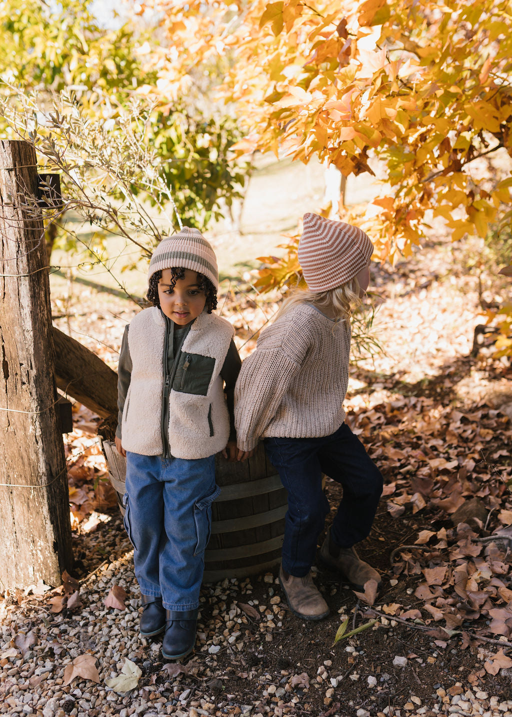 Berlin Merino Beanie Biscuit & Cream Stripe on child side view playing in nature – kids knitted merino wool striped beanie with pointed top – Acorn Kids