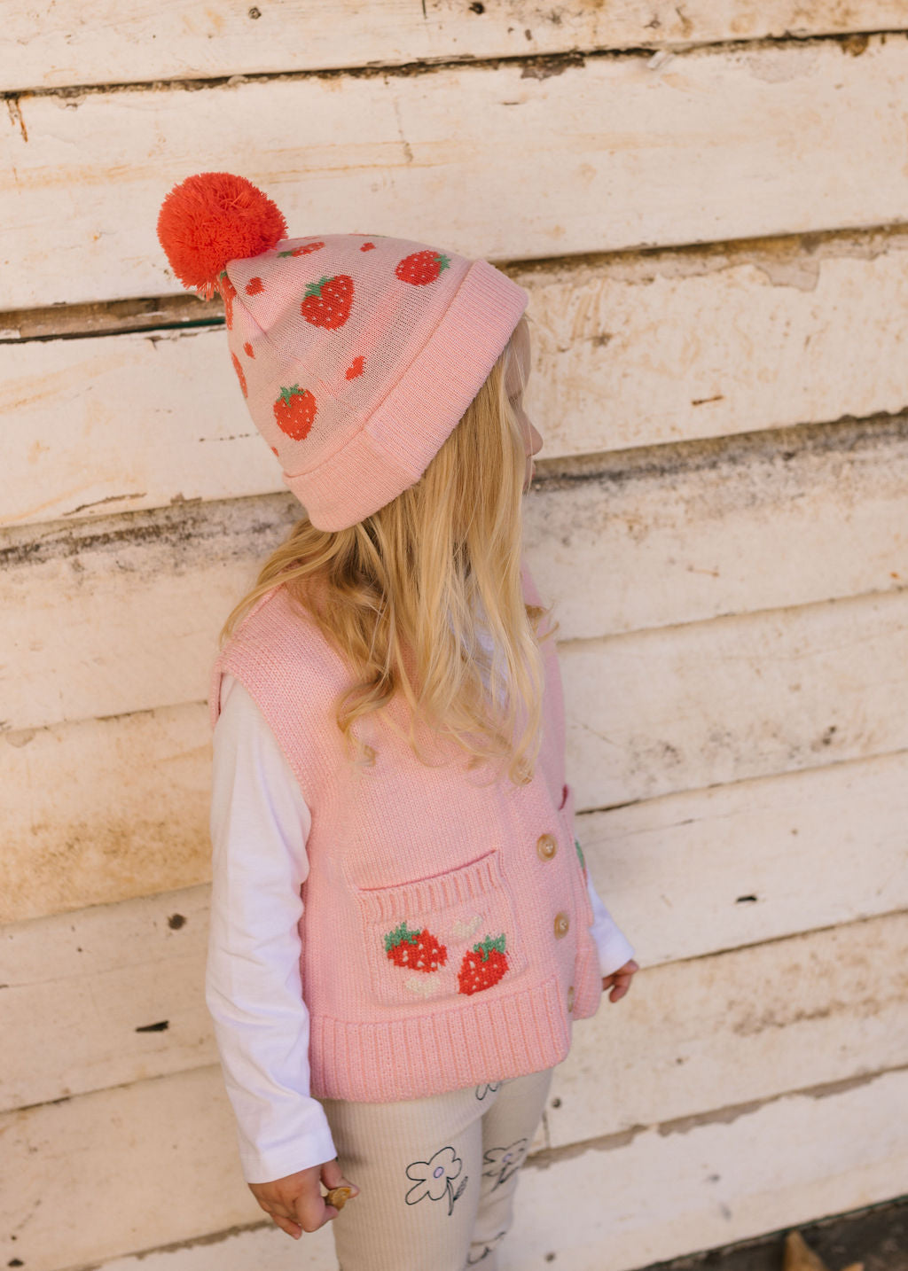 Strawberry Fields Merino Beanie on child side view – kids knitted merino wool beanie with strawberry design and pom pom – Acorn Kids