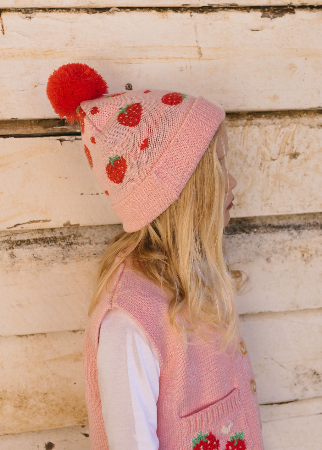 Strawberry Fields Merino Beanie on child side view close up – kids knitted merino wool beanie with strawberry design and pom pom – Acorn Kids