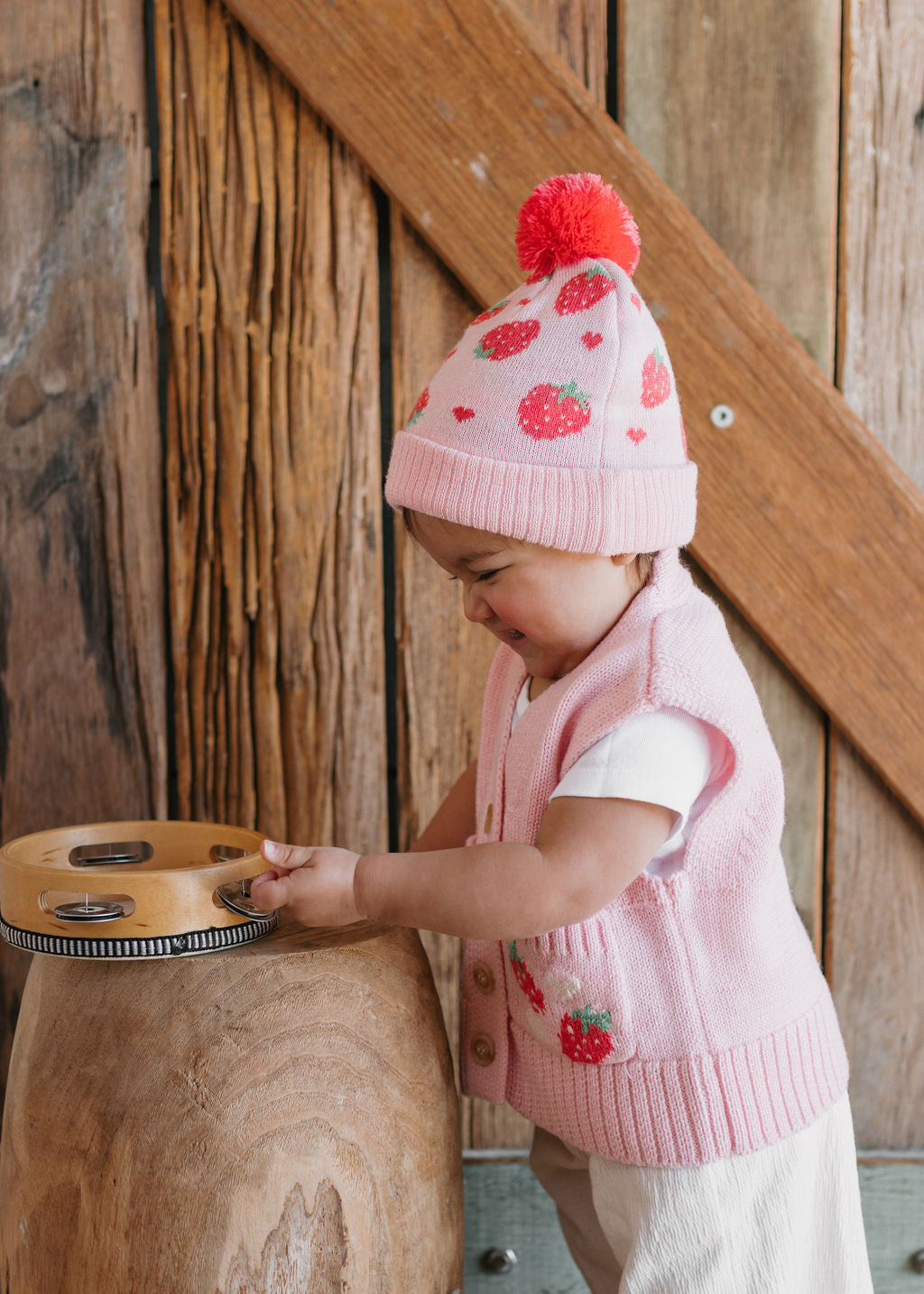 Strawberry Fields Merino Beanie on child side view – kids knitted merino wool beanie with strawberry design and pom pom – Acorn Kids