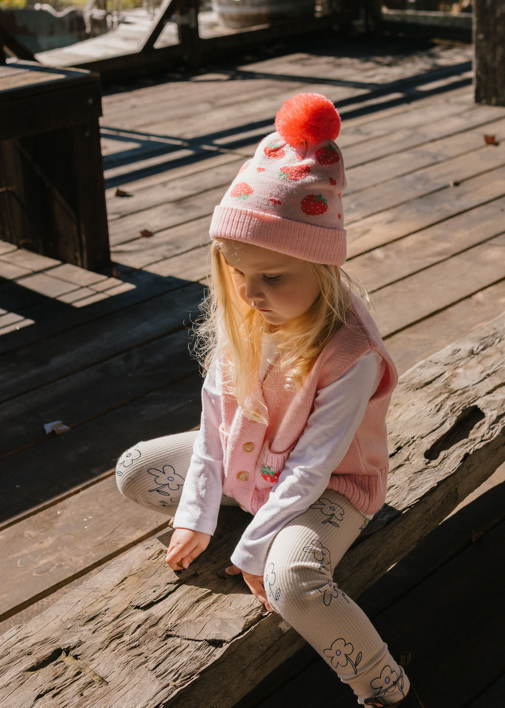 Strawberry Fields Merino Beanie on child playing – kids knitted merino wool beanie with strawberry design and pom pom – Acorn Kids