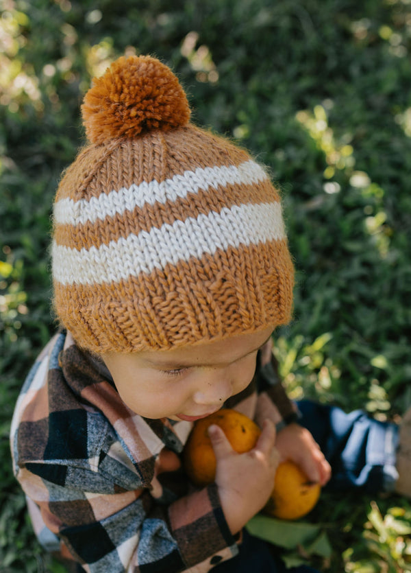 Retro Beanie Caramel & Cream on child close up – kids hand-knitted striped beanie with pom pom in soft wool blend – Acorn Kids