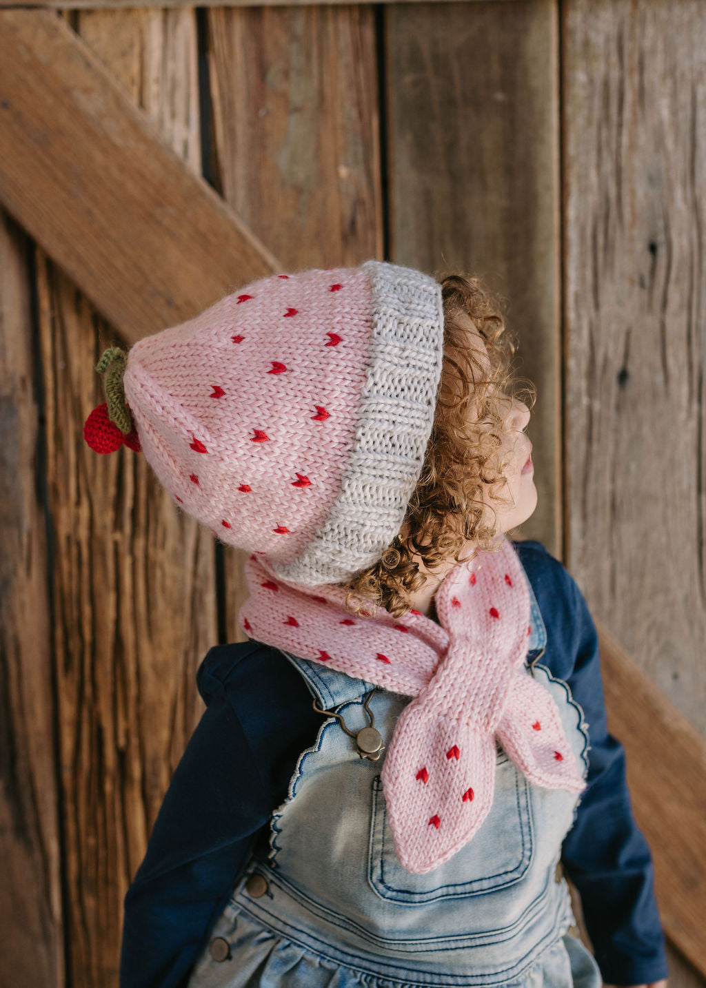 Cherry Beanie – kids hand-knitted pink beanie with crochet cherry and soft wool blend shown on child - side view – Acorn Kids