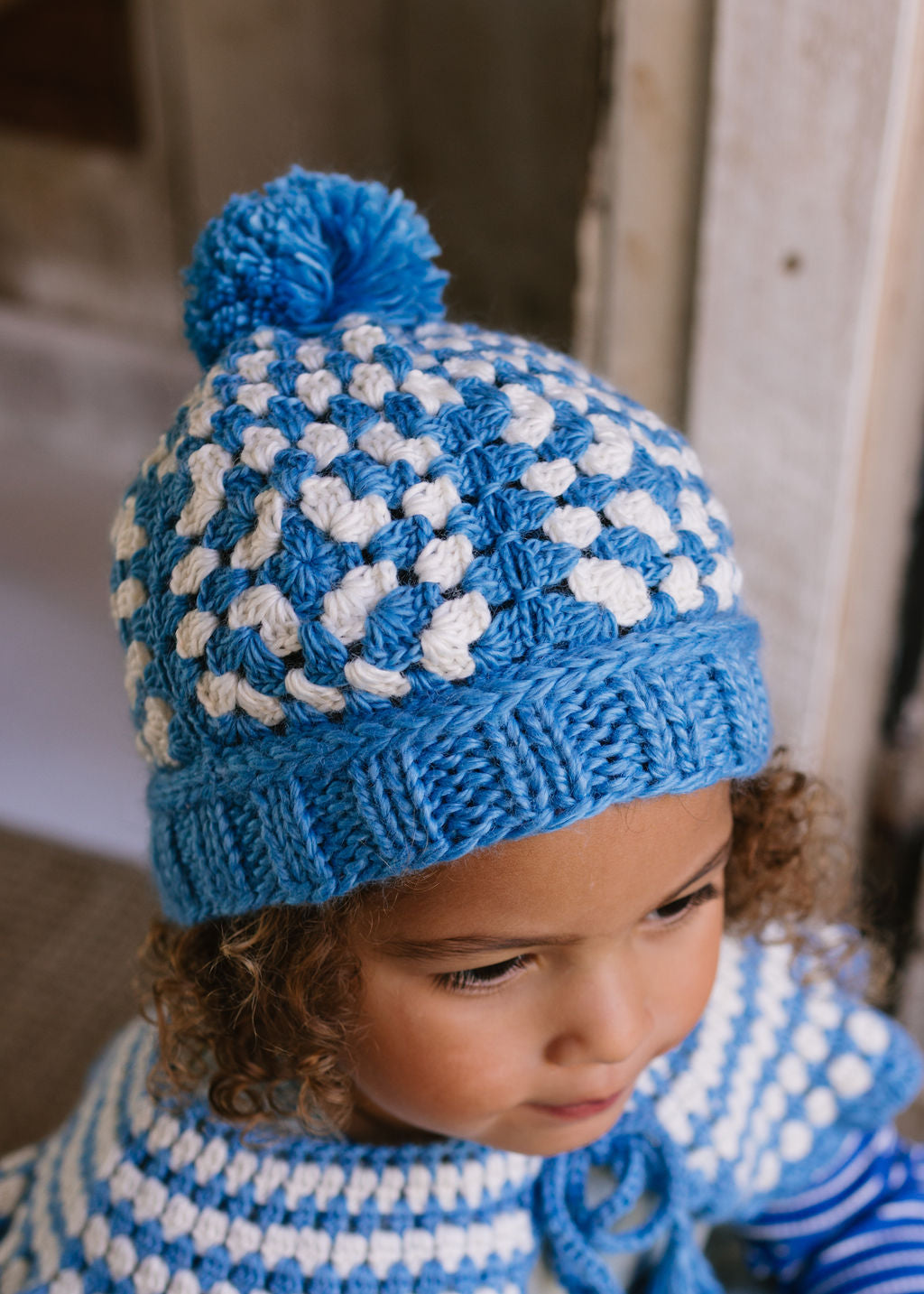 Boho Beanie Blue on child close up top view – kids hand-crocheted beanie with two-tone granny square pattern and pom pom – Acorn Kids