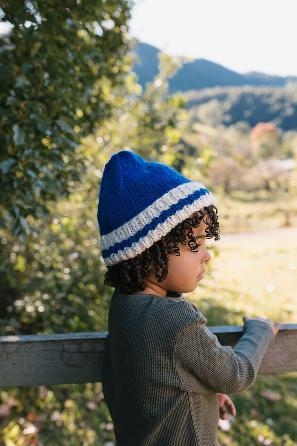 Child wearing Denmark Beanie Blue & Cream side view close up – kids striped knit beanie with pointed crown – Acorn Kids 