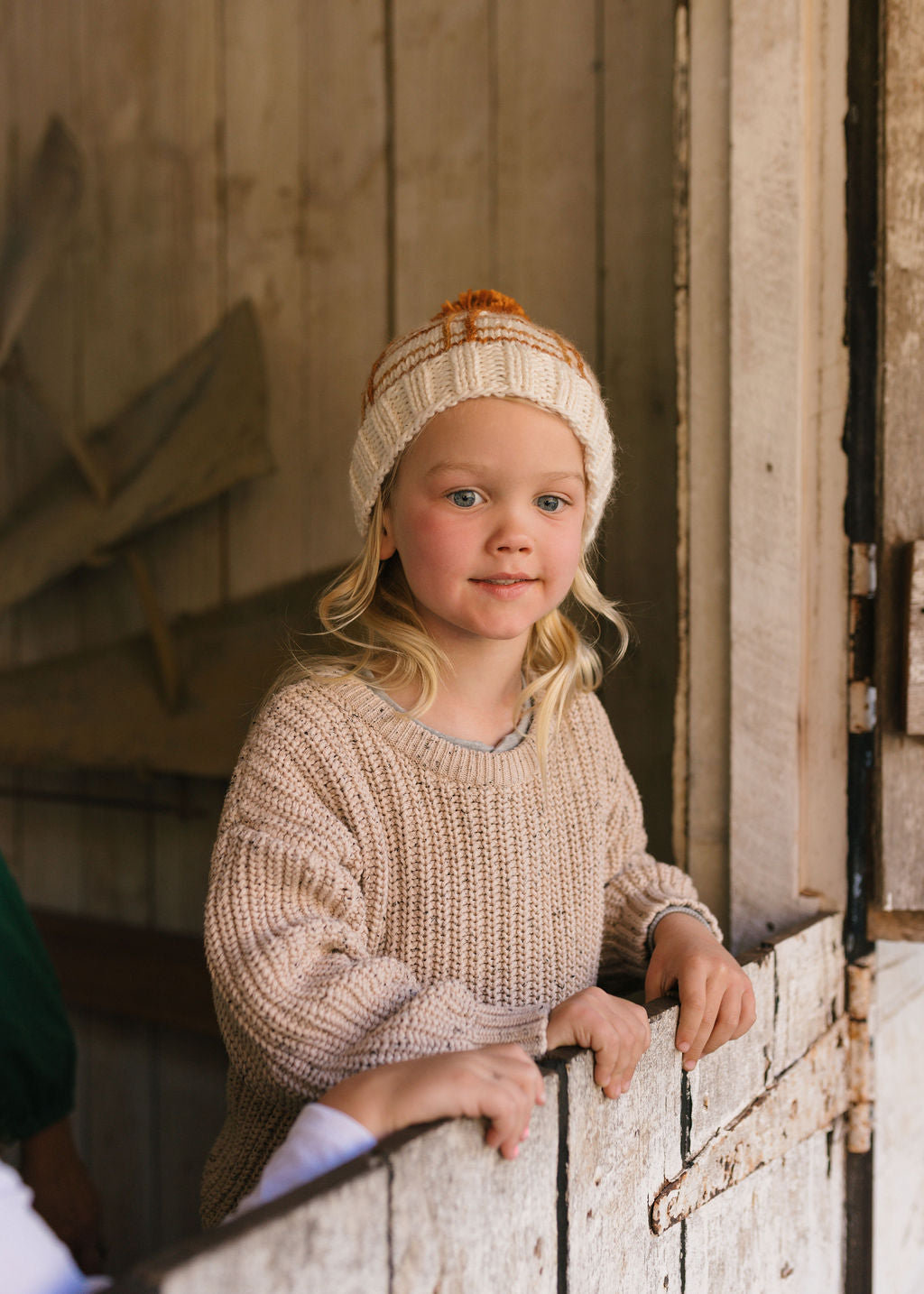 Crossroads Beanie Brown and Caramel on child front view – kids hand-knitted checked beanie with colourful pom pom in soft wool blend – Acorn Kids