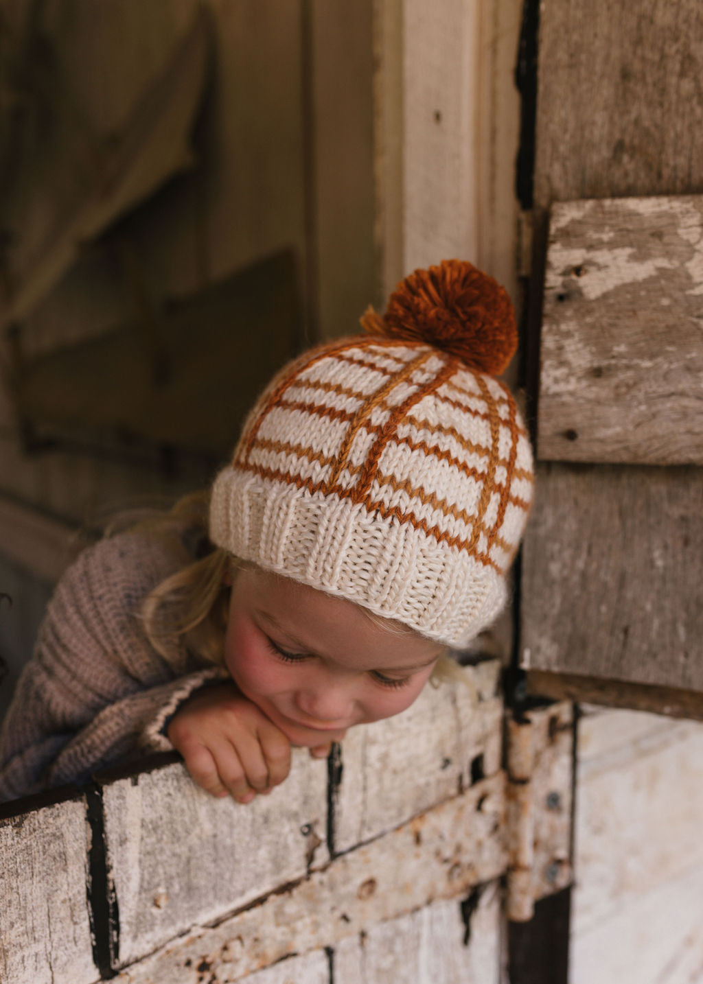 Crossroads Beanie Brown and Caramel on child close up – kids hand-knitted checked beanie with colourful pom pom in soft wool blend – Acorn Kids
