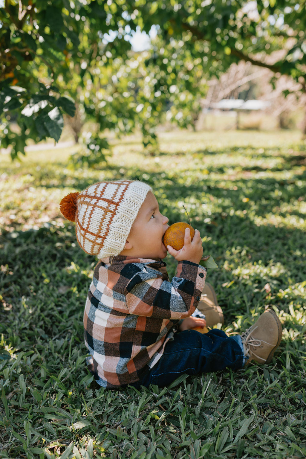 Crossroads Beanie Brown and Caramel on baby side view – kids hand-knitted checked beanie with colourful pom pom in soft wool blend – Acorn Kids
