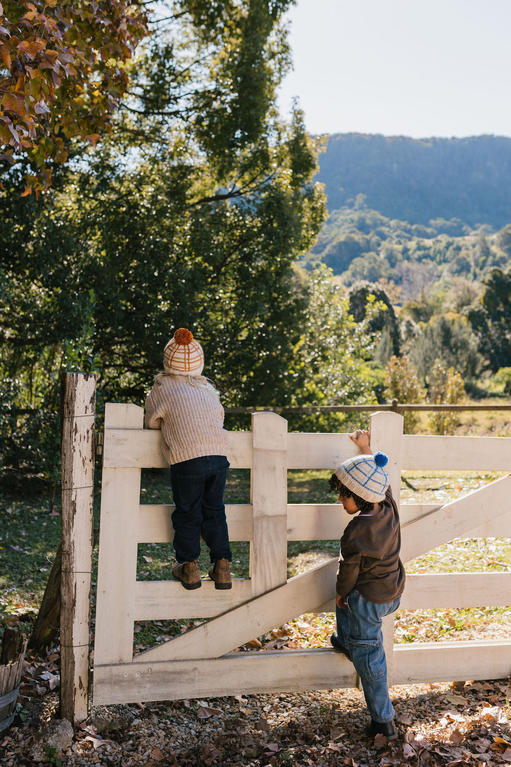 Crossroads Beanie Blue on child in nature – kids hand-knitted checked beanie with colourful pom pom in soft wool blend – Acorn Kids
