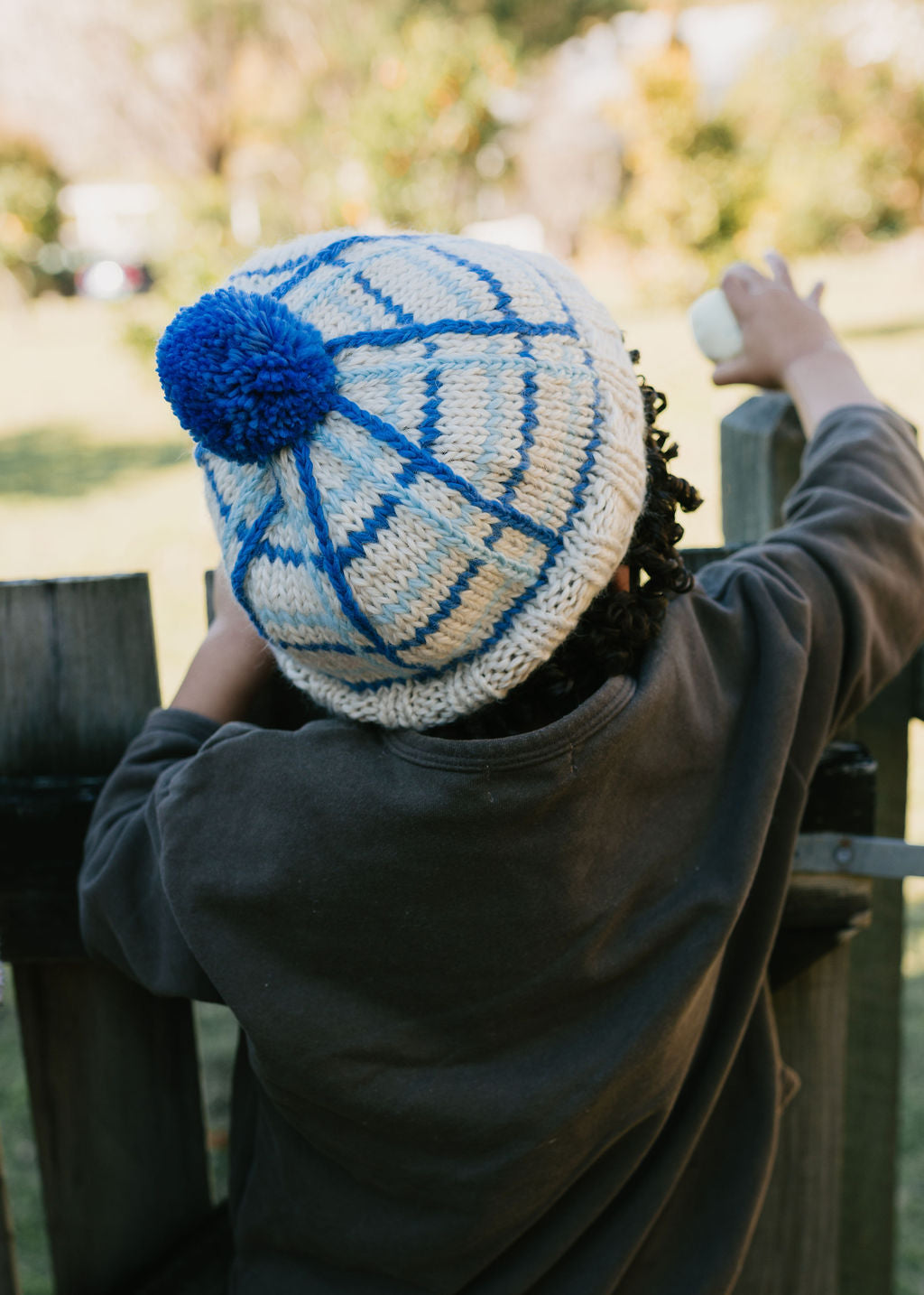 Crossroads Beanie Blue on child back view close up – kids hand-knitted checked beanie with colourful pom pom in soft wool blend – Acorn Kids