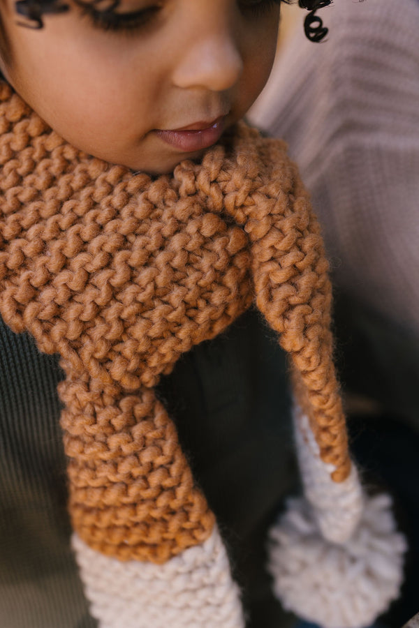 Retro Scarf Caramel & Cream on child close up – kids hand-knitted two-tone scarf with pom poms in soft wool blend – Acorn Kids
