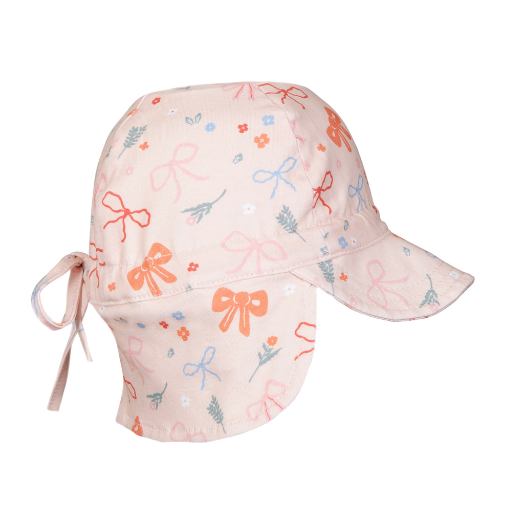 A light pink sun hat for children featuring a playful pattern of orange bows, blue bows, and small floral motifs. The hat includes a wide brim, a chin strap with ties, and a neck flap.